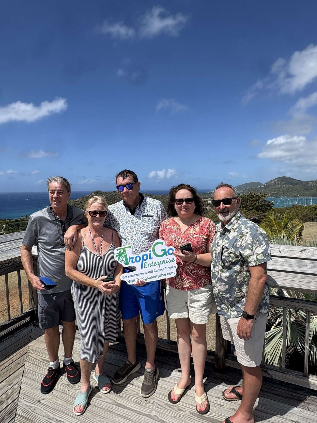 Five guests with a TropiGo sign at a scenic lookout.